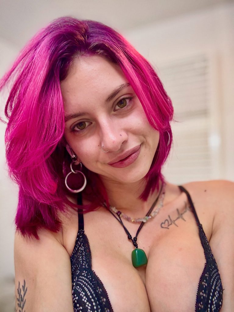 Close-up of Jazzz_mel with pink hair, piercing, and a direct gaze as an authentic FansyMe creator.