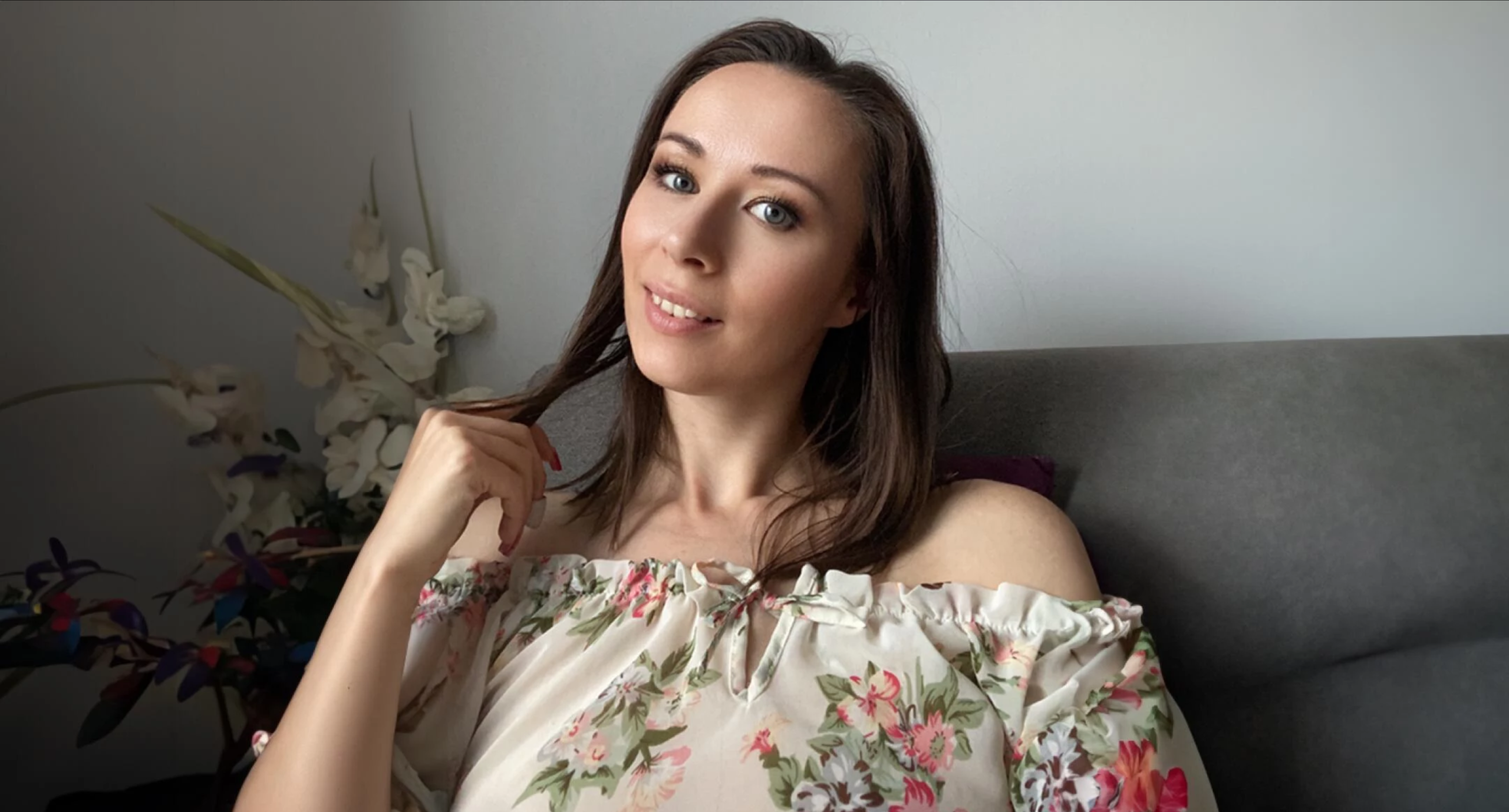 Ronya Rabe lächelt entspannt im floral gemusterten Kleid – authentisches FansyMe Erotikmodel mit natürlicher Ausstrahlung.