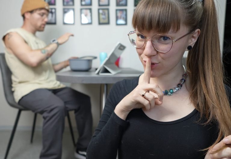Anne von BettDuett macht Psst-Geste während Eddi ahnungslos am Tisch sitzt