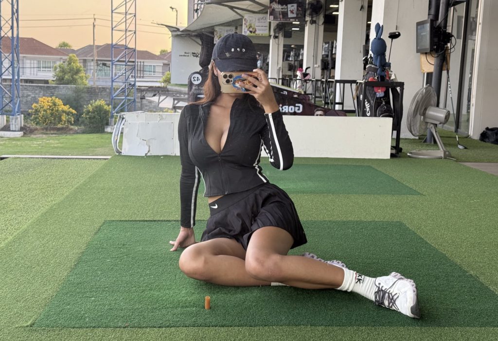 Jane Meow takes a mirror selfie at an indoor sports facility, wearing a black sports outfit with a cap and white sneakers.