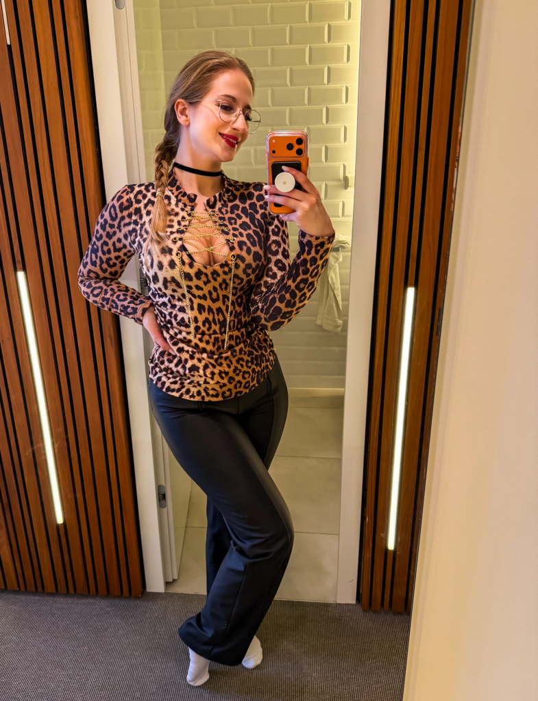 Mika Nox posiert in einem Leoparden-Outfit vor einem Spiegel und macht ein Selfie für ihr FansyMe-Profil.