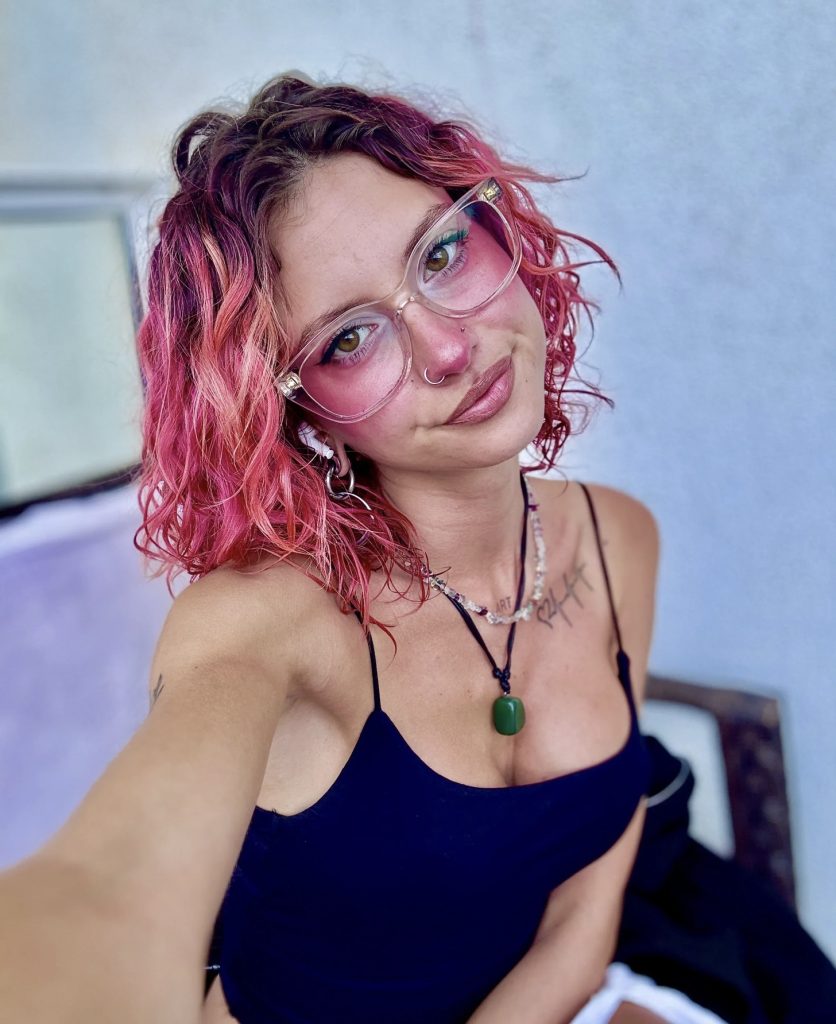 Melanie Jasmin selfie with curly pink hair and transparent glasses